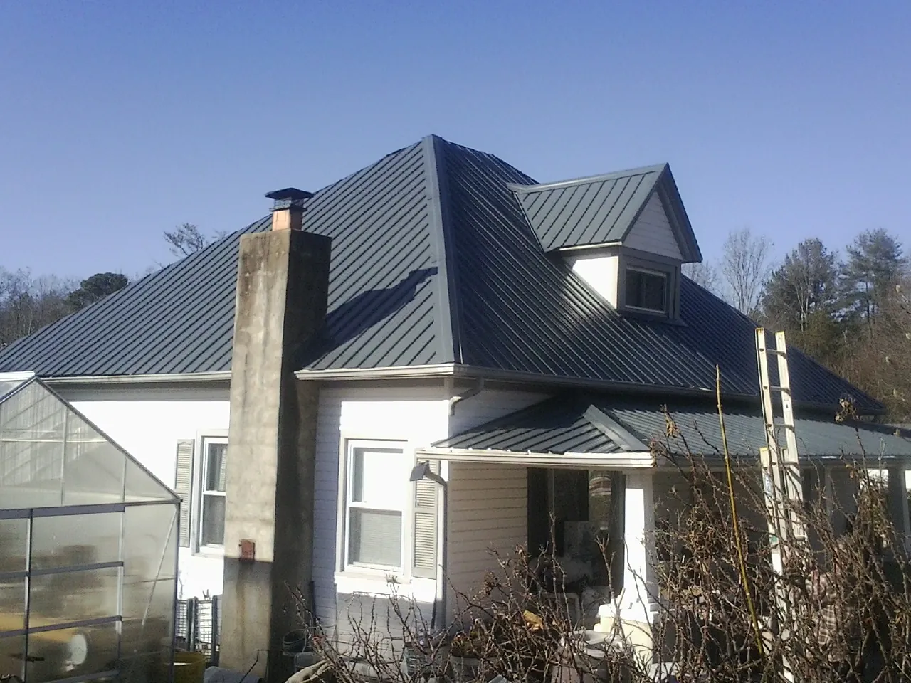 Dark blue standing seam metal roof on a white farmhouse with dormer — Slate & Tile Roof Repair by Roofing Brothers in Brooktondale