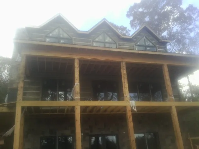 Dormers and porch framing on a large log home under construction — Roof Coating work by our crew in Brooktondale