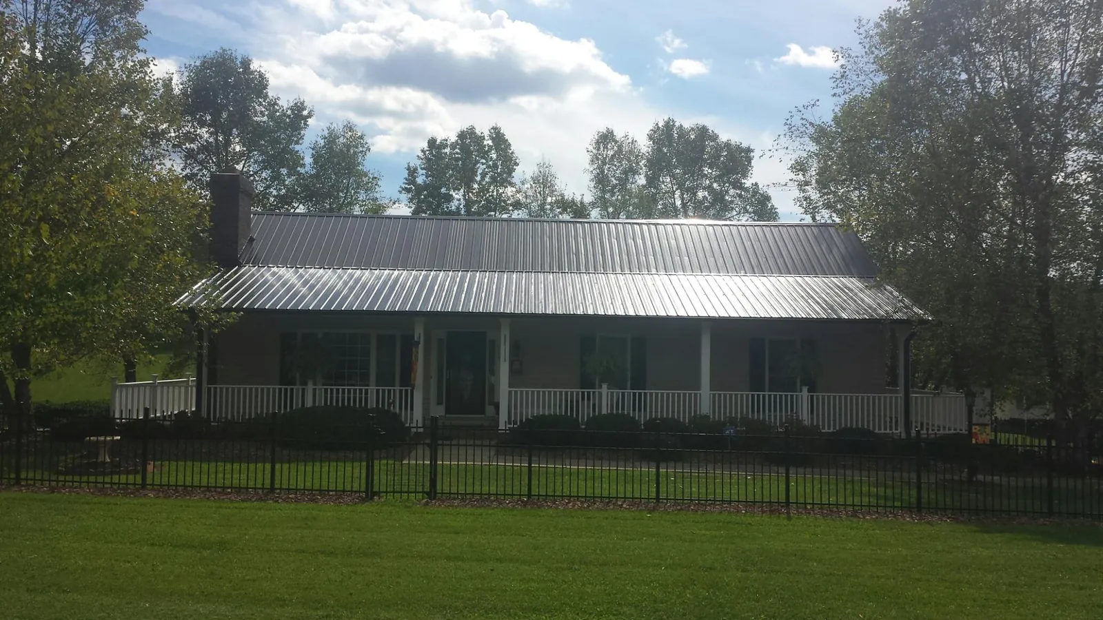 Gray metal roof on a brick ranch with a full width front porch — Gutter Guard Installation work by our crew in Brooktondale