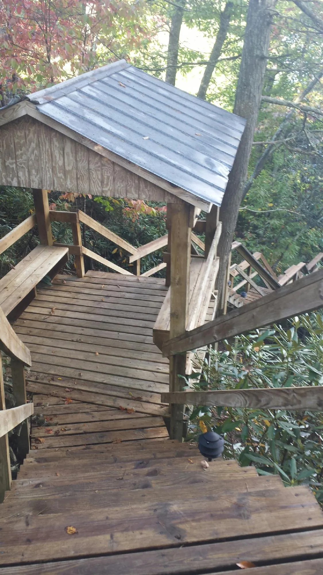 Metal roofed shelter over wooden steps on a wooded walkway — Skylight Repair & Installation work by our crew in Brooktondale