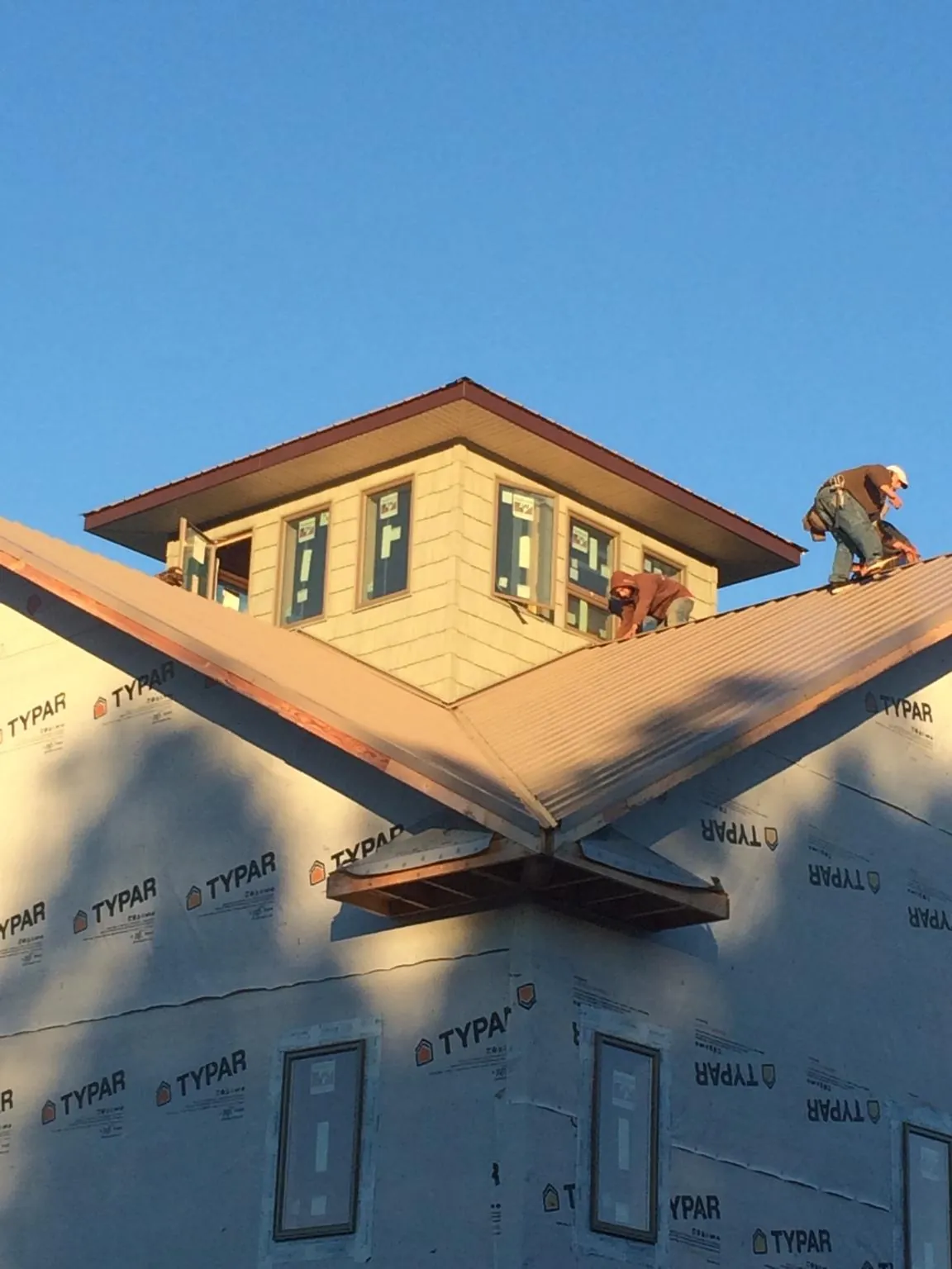 Roofers working around a rooftop cupola on a new metal roof at sunset — Roof Waterproofing in Brooktondale by Roofing Brothers
